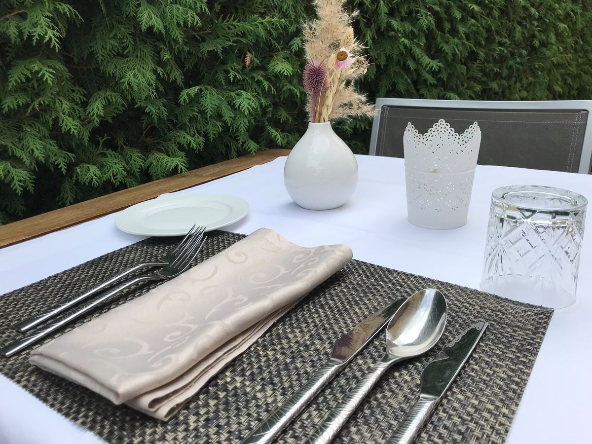 Festlich eingedeckter Tisch mit weißer Tischdecke, Stoffservietten, Besteck und Trockenblumen