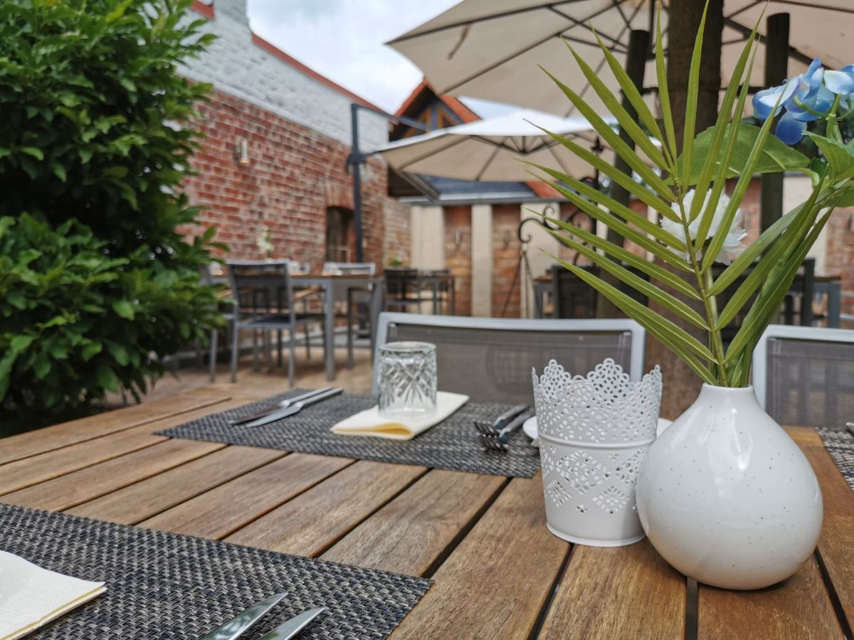 Eingedeckter Tisch auf der Gartenterrasse mit Vasen und Grünpflanze