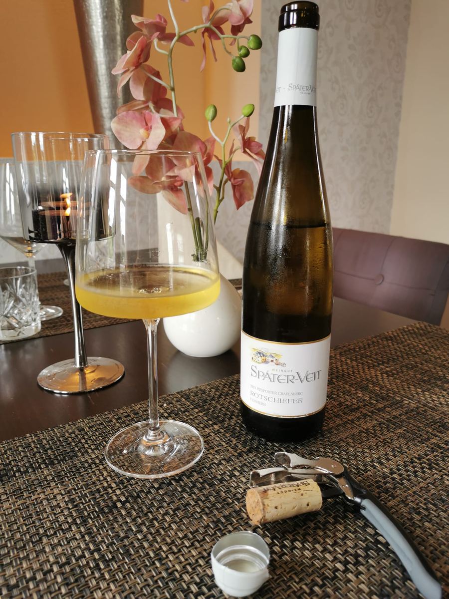 Weißweinflasche mit zwei Gläsern und Orchidee auf einem eingedeckten Tisch